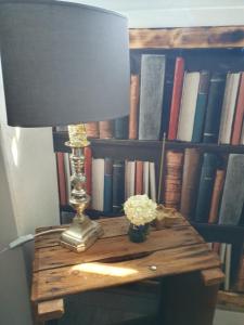 a table with a lamp and a book shelf with books at L'Atelier in Lannion