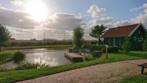 a green building next to a river with a boat at Habbo's Kojen in Neuharlingersiel