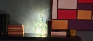 a bottle with a candle on a table with books at Casa curro in Baena