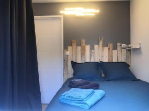 Una cama con almohadas azules y toallas. en Accès direct à la PLAGE de Mr HULOT Saint Marc sur Mer près de La Baule - Parking privé, en Saint-Nazaire