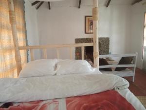 een bed met witte lakens en kussens in een kamer bij Eco Farm in Karatu
