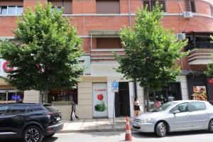 Deux voitures garées dans la rue devant un magasin dans l'établissement City Center Rooms Durres, à Durrës