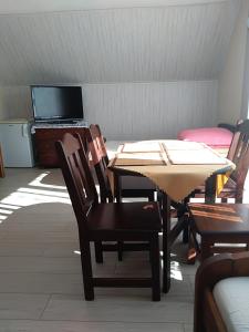 a dining room with a table and chairs and a television at Uroczy Zakątek in Krynica Morska