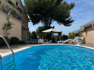 a swimming pool in a villa with a tree at Holiday Home Villa Romantica in Sveti Filip i Jakov