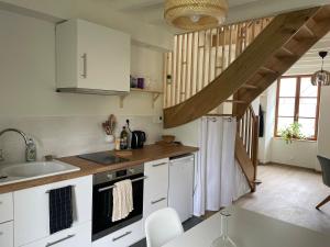 オービニー・シュル・ネールにあるPetite maison Duplexの白いキャビネットと階段付きのキッチン