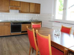 a kitchen with a wooden table with chairs and a stove at Miss Comfortable Holiday Residence in Bad Berleburg