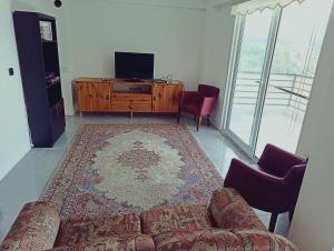 a living room with a couch and a flat screen tv at Kuzine Garden in Pamukkale