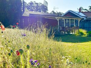 a red house with a field of grass and flowers at 4 person holiday home in ÅHUS-By Traum in Åhus +13 photos