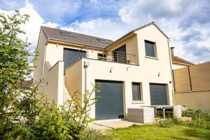 a white house with two garage doors at Residence VELOURS avec terrasse , jardin et parking in Champigny-sur-Marne