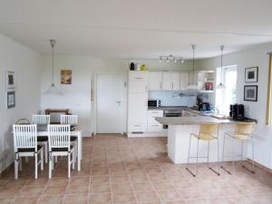 een keuken met witte kasten en een tafel en stoelen bij House Saga - Huus Asgard in Nieby