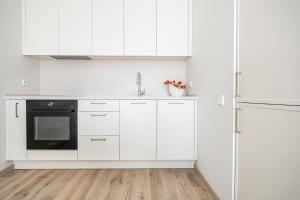 a white kitchen with white cabinets and a sink at Vanagupės Perlas in Palanga