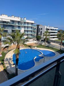 a swimming pool with a palm tree and a building at Apartamento Augusta Cambrils Lux con vista al mar in Cambrils