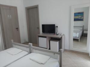 a bedroom with two beds and a flat screen tv at Meto Rooms in Sarandë