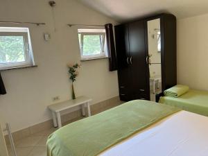 a bedroom with two beds and a table and two windows at Haus Karin in Lovran