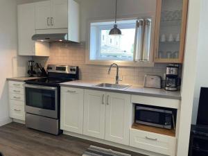 a kitchen with white cabinets and a sink and a window at Modern apartment - 1 Bed in Caraquet