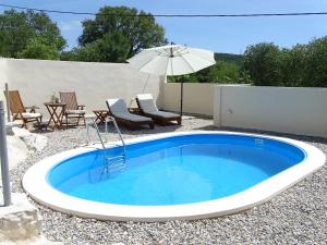 a swimming pool with an umbrella and chairs and a table at Holiday home Mimara in KoruÅ¡ce