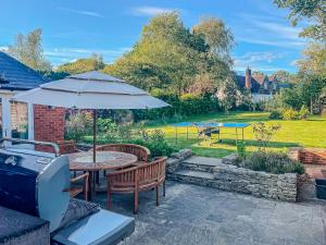 a patio with a table and chairs and an umbrella at Beautiful Cottage in Brockenhurst with Forest View in Brockenhurst