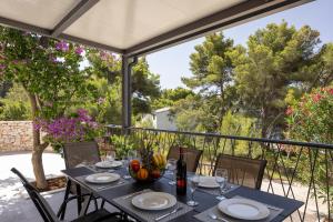 a table on a balcony with a view of trees at Villa Mala Smišna Poolside Paradise by the Sea in Maslinica