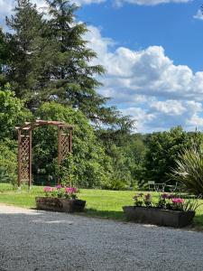 een park met twee bloemperken en een houten boog bij La Colline de Tilleul - Les Deux Puits - Cosy Cottage with swimming pool near Aubeterre in Saint-Romain