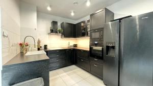 a kitchen with black cabinets and a stainless steel refrigerator at Stylowy Apartament w sercu Uzdrowiska in Jedlina-Zdrój