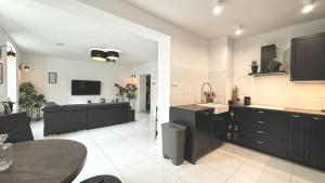 a large kitchen with black cabinets and a table at Stylowy Apartament w sercu Uzdrowiska in Jedlina-Zdrój +8 photos