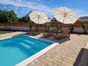 una piscina con dos sombrillas y dos sillas en Rustic House Konfidenca, en Biograd na Moru