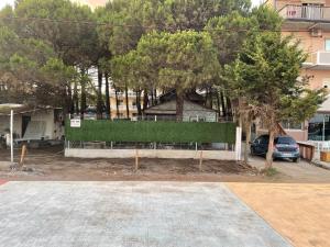 a house with a hedge in front of a parking lot at Pinehouse Velipoja in Velipojë +15 photos