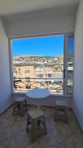 a table and chairs in a room with a large window at Bega Apartment in Sarandë +6 photos