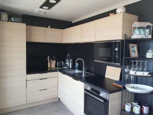 une cuisine avec des armoires en bois et un comptoir noir dans l'établissement Cottage 4-6 pers-piscine chauffée-150m plage, à Jullouville