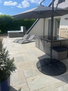 eine Terrasse mit einem Glastisch und einem Sonnenschirm in der Unterkunft Jolie maison proche plages et golf in Bénodet
