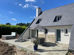 eine Terrasse mit zwei Stühlen und einem Sonnenschirm in der Unterkunft Jolie maison proche plages et golf in Bénodet
