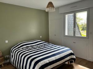 ein Schlafzimmer mit einem gestreiften Bett und einem Fenster in der Unterkunft Jolie maison proche plages et golf in Bénodet + 36 Fotos