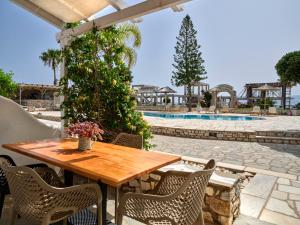 a wooden table and chairs on a patio with a pool at Fyrogenis palace in Ambelas