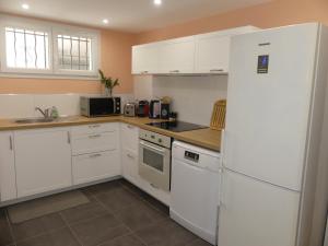 a kitchen with white cabinets and a white refrigerator at Le cocon des passons 3 pièces 70m2 in Aubagne