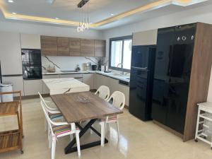 a kitchen with a wooden table and a black refrigerator at Grande Villa Familiale Route Du Phare in Djerba