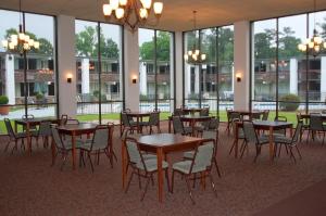 Habitación grande con mesas, sillas y ventanas. en Landmark Inn en Hartsville