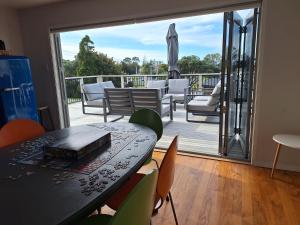 a room with a table and chairs on a deck at The Beach Bach in Waihi Beach