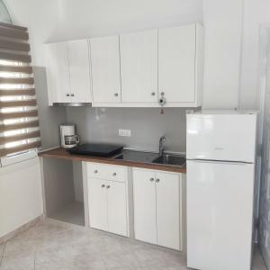 a kitchen with white cabinets and a sink and a refrigerator at Il Margio Studio in Tinos Town