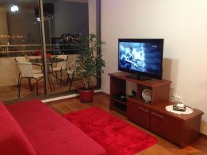 sala de estar con sofá rojo y TV de pantalla plana en Apartamento Castilla, en Viña del Mar