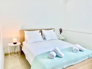 a white bedroom with two towels on a bed at Riverside apartments in Lefkada