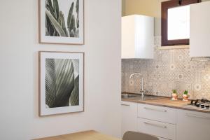 a kitchen with white cabinets and a picture on the wall at Le Case di Salvia in San Vincenzo +148 photos