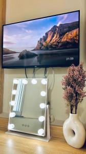 Un televisor en una pared con un jarrón y un estante. en Riverside apartments, en Lefkada