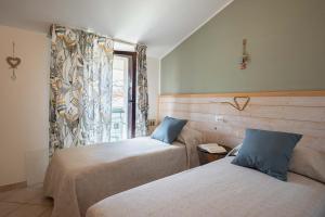 two beds in a room with a window at Le Case di Salvia in San Vincenzo