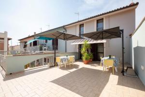 a patio with tables and umbrellas in front of a house at Le Case di Salvia in San Vincenzo