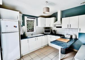 a kitchen with white cabinets and a white refrigerator at Pins & Lacs in Biscarrosse