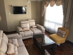 a living room with a couch and chairs and a tv at C14 de Obrajes in La Paz