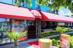 a store front with red awnings and palm trees outside at Brand Business Hotel in Corlu