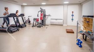 a gym with two women exercising on tread machines at Alojate en METRA Puerto Norte, luminoso estudio con pileta, gym y balcon in Rosario