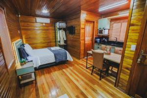 a bedroom with a bed and a desk and a kitchen at Recanto da Maju in Bom Jardim da Serra