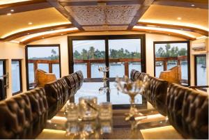 a dining room with a table with chairs and windows at Northstar 1 Bedroom Ac Private Houseboat With All Meals in Alleppey